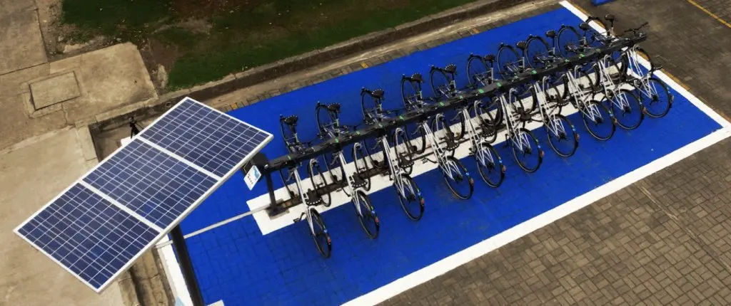 Estación de bicicletas con parqueaderos para ciclas y paneles solares en infraestructura de movilidad sostenible para empresas y universidades en Colombia